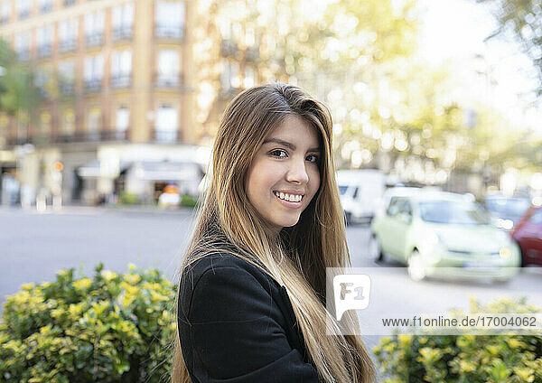 Junge Frau lächelt  während sie in der Stadt steht