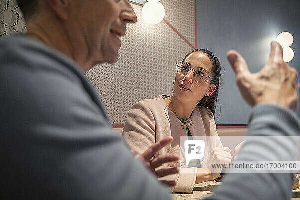 Geschäftsfrau hört einem Kollegen zu  während sie in einem modernen Cafe sitzt