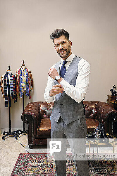 Portrait of smiling man in gray waistcoat in tailors boutique
