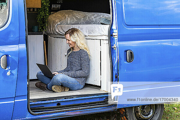 Woman with blond hair working on laptop in motor home