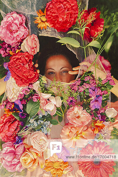 Schöne Frau schaut durch Schleier mit Blumen