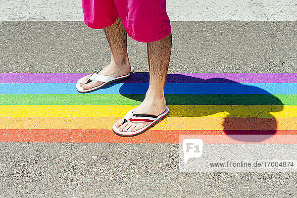 Mann steht auf einem Fußgängerüberweg in Regenbogenfarben