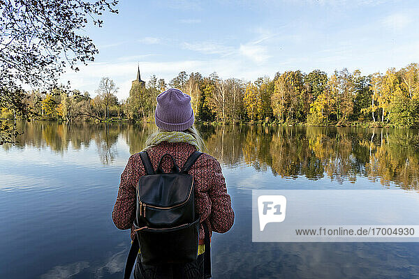 Mid erwachsene Frau mit Rucksack Blick auf See gegen Himmel im Wald