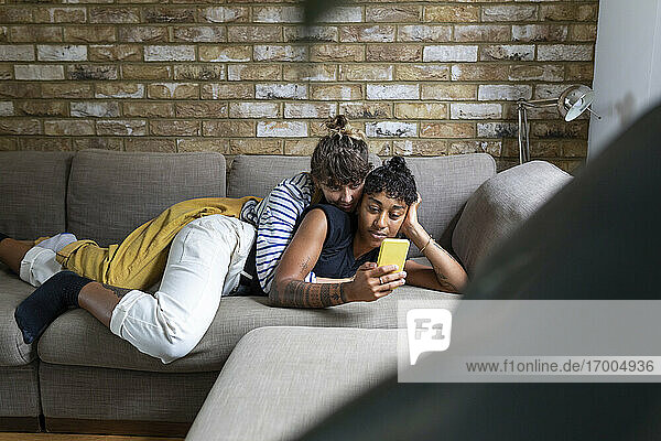 Frau  die ihre Freundin umarmt und ein Selfie mit dem Handy macht  während sie sich zu Hause entspannt