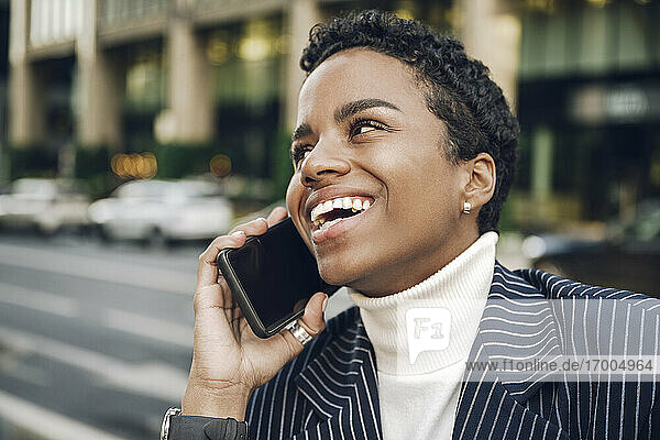 Happy young businesswoman looking away while talking on smart phone