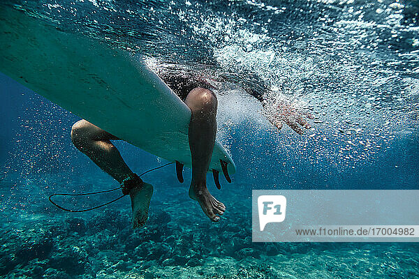 Male surfer sitting on surfboard while surfing in sea at Maldives
