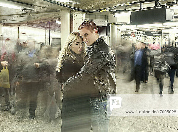 Junges Paar umarmt sich in der U-Bahn-Station während der Hauptverkehrszeit
