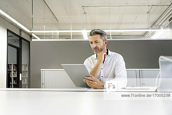 Businessman using digital tablet while sitting at office