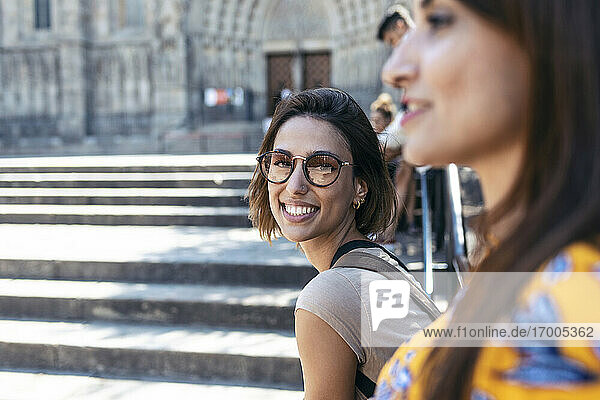 Lächelnde Frau sitzt mit einem Freund auf dem Platz der Kathedrale von Barcelona in Barcelona  Katalonien  Spanien