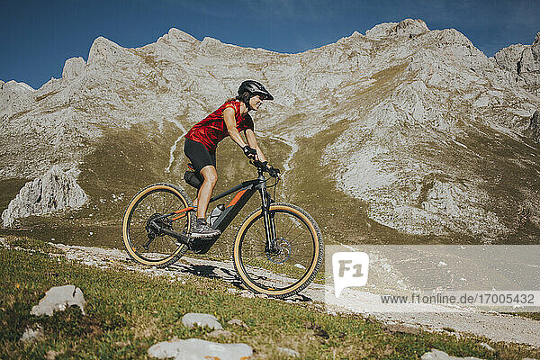 Radfahrerin beim Radfahren in der Nähe eines Felsenberges im Nationalpark Picos de Europa  Kantabrien  Spanien