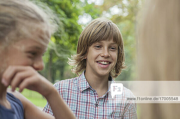 Glücklicher Junge im Gespräch mit Freunden in einem öffentlichen Park