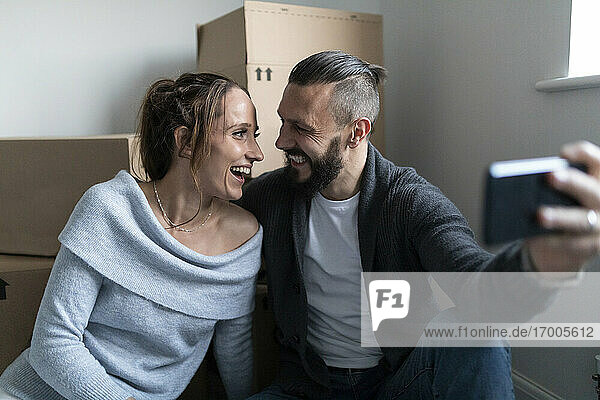 Fröhliches Paar  das sich beim Selfie in seinem neuen Zuhause von Angesicht zu Angesicht sieht