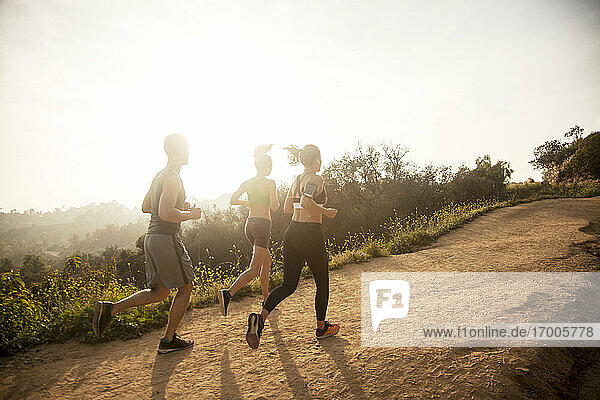 Man and woman exercising while running together on mountain path