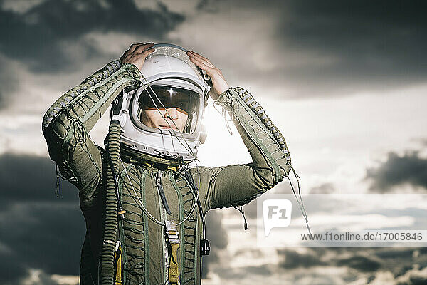 Man posing dressed as an astronaut with dramatic clouds in the background