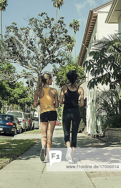 Multi-ethnic friends jogging along streets on sunny day