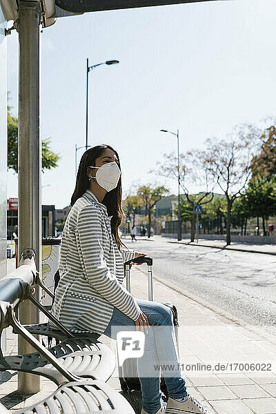 Frau wartet an einem sonnigen Tag während der COVID-19-Pandemie auf den Bus