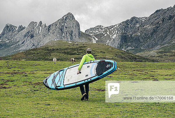 Älterer Mann  der ein Paddleboard trägt  während er durch eine Landschaft läuft  Leon  Spanien