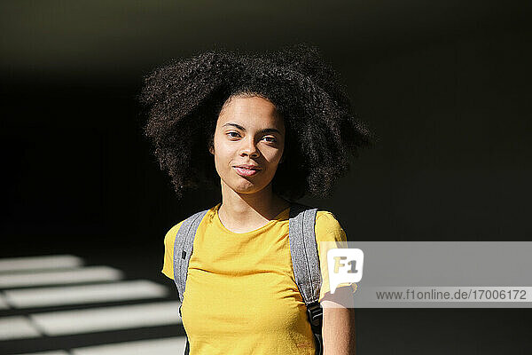 Junge Studentin  die eine Tasche trägt  während sie im Korridor einer Universität steht