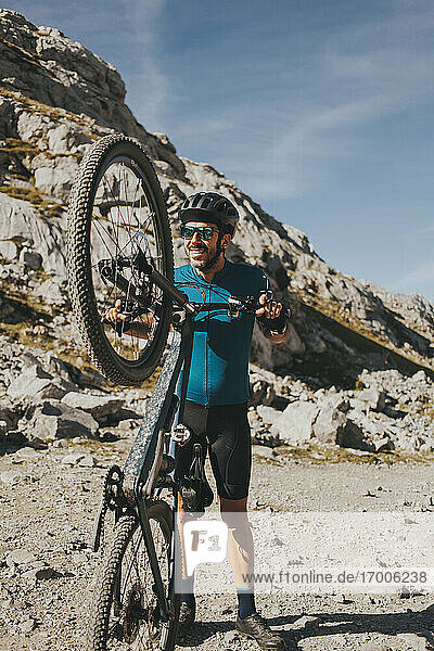 Verspielter männlicher Radfahrer mit Mountainbike an einem sonnigen Tag  Nationalpark Picos de Europa  Kantabrien  Spanien
