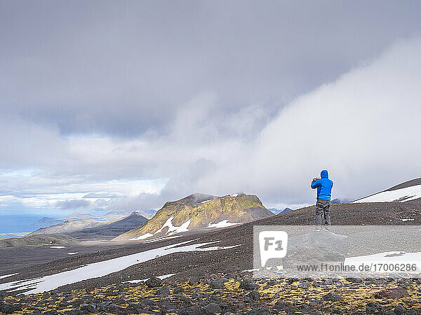 Male hiker standing on top of boulder in Snaefellsjokull National Park  Iceland