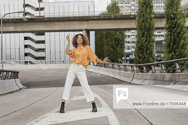 Unbekümmerte junge Frau tanzt auf einer Brücke in der Stadt