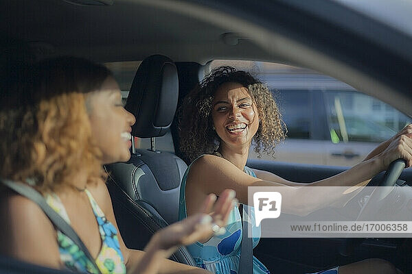 Woman laughing while looking at female friend in car