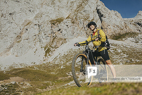 Lächelnde Radfahrerin mit Mountainbike an einem sonnigen Tag im Nationalpark Picos de Europa  Kantabrien  Spanien