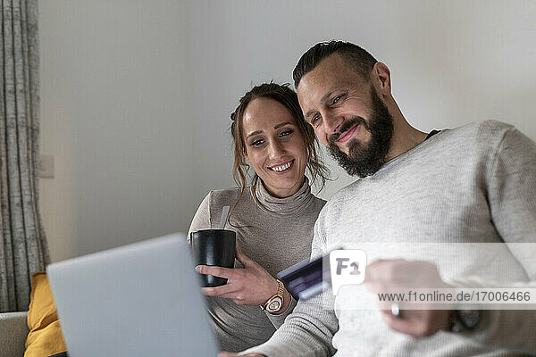Lächelndes Paar beim Online-Shopping mit dem Laptop zu Hause