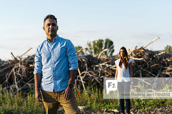 Junger Mann mit Freundin im Hintergrund auf einem Feld stehend