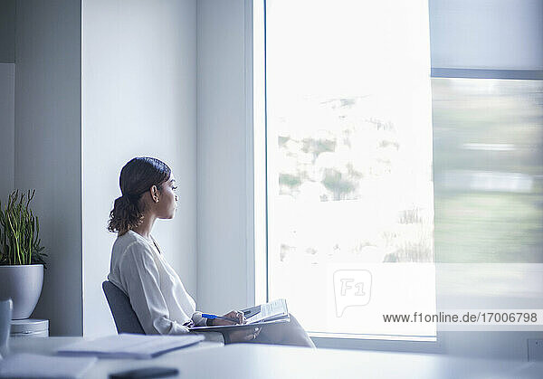 Junge Unternehmerin sitzt mit Dokument im Büro