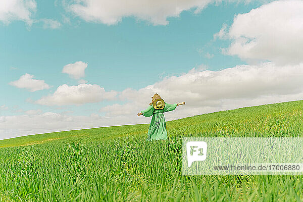 Rückenansicht einer Frau in grünem Kleid  die auf einem Feld läuft