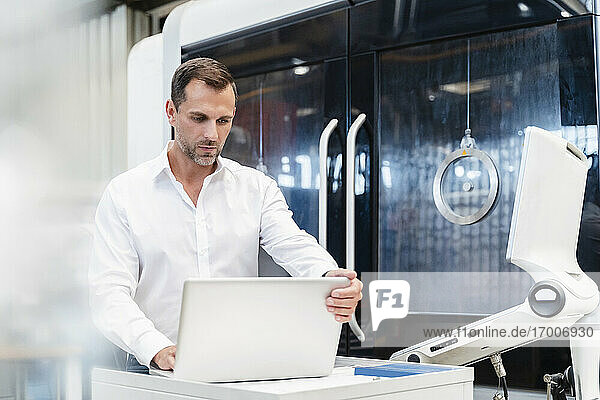 Männlicher Unternehmer arbeitet an einem Laptop in einer Fabrik