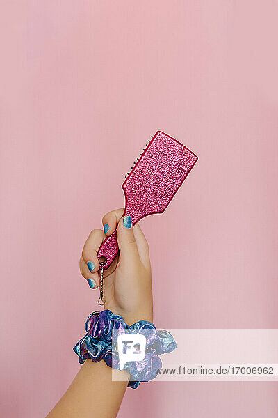 Hand of teenage girl holding pink hair brush