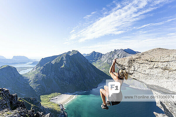 Mittlere erwachsene Frau hängt am Rande eines Berges in Ryten  Lofoten  Norwegen