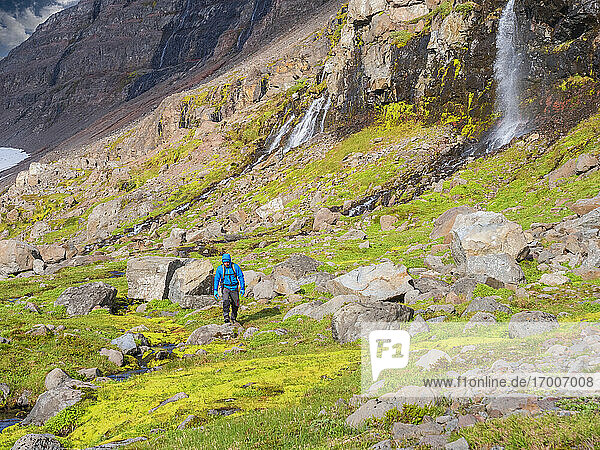 Männlicher Wanderer zwischen Felsbrocken in einem isländischen Tal