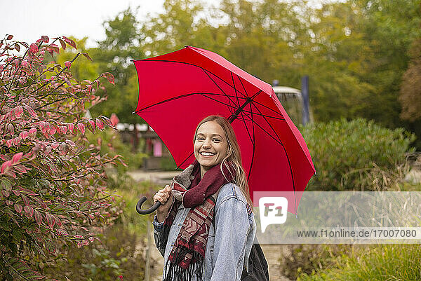 Glückliche Frau mit Regenschirm im Park