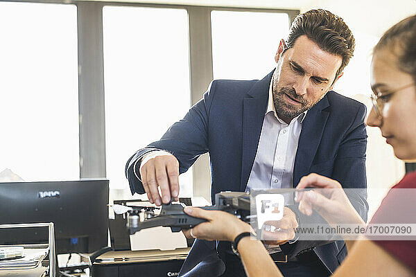 Businessman examining quadcopter with colleague at office