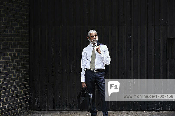 Porträt eines stilvollen älteren Geschäftsmannes mit grauem Haar vor dunklem Hintergrund