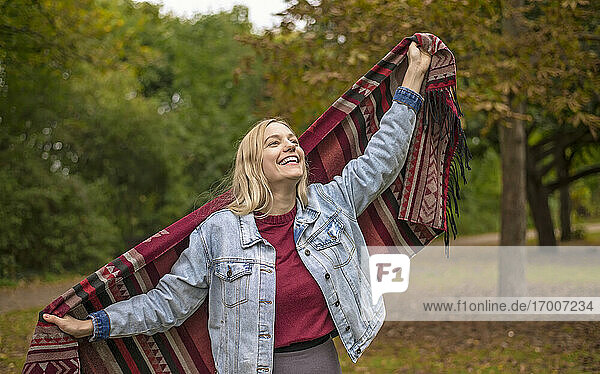 Glückliche Frau mit Schal im herbstlichen Park stehend