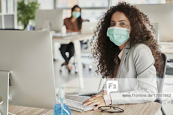 Junge Geschäftsfrau an ihrem Schreibtisch während der Pandemie