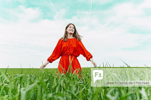 Lächelnde Frau in rotem Kleid auf einem Feld