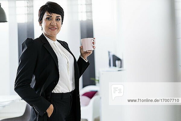 Portrait of businesswoman posing with mug in hand