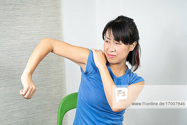 Asiatische Frau mit Schulterschmerzen