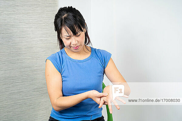 Asiatische Frau mit Schmerzen in ihrer Hand.