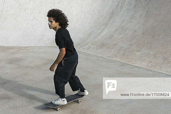 Sportsman skateboarding while practicing with at skateboard park