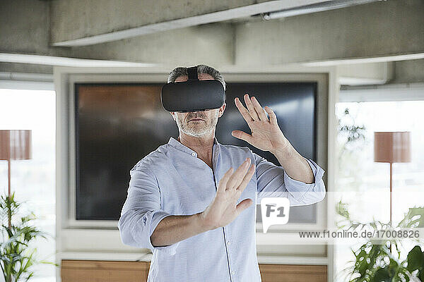 Businessman wearing virtual reality headset standing at home