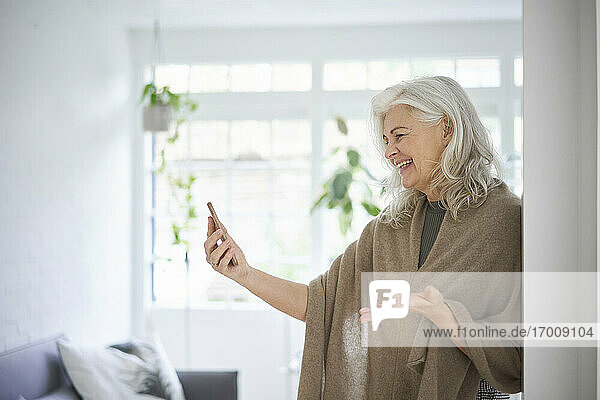 Glückliche Frau im Ruhestand bei einem Videogespräch über ihr Smartphone zu Hause