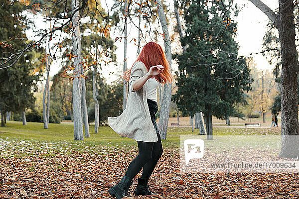 Unbeschwerte Frau mit braunen Haaren tanzt auf dem Land im Park im Herbst