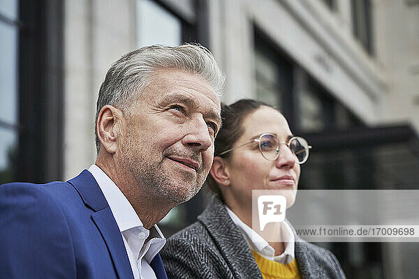 Thoughtful businessman with businesswoman looking away