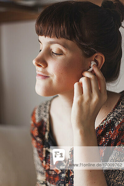 Young woman putting in wireless earphones